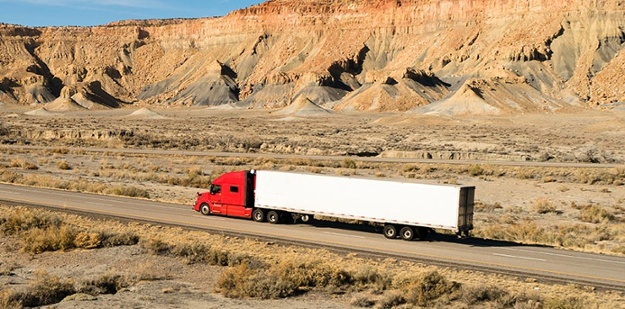 semi truck driving down an empty road 