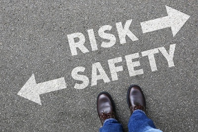 man standing over a risk vs safety sign 